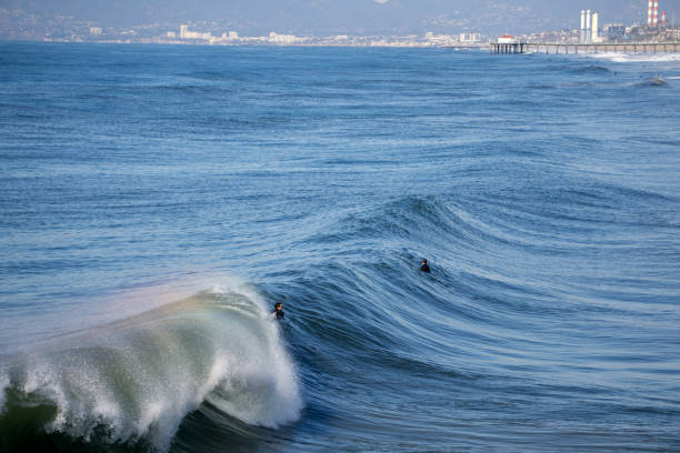 From atop the Hermosa Beach Pier, two surfers wait for the perfect wave.