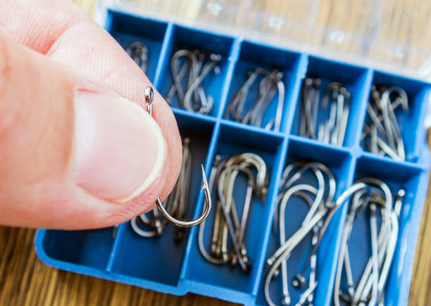 A man is selecting a fishhook from a box, preparation for fishing. Part of body, selective focus.