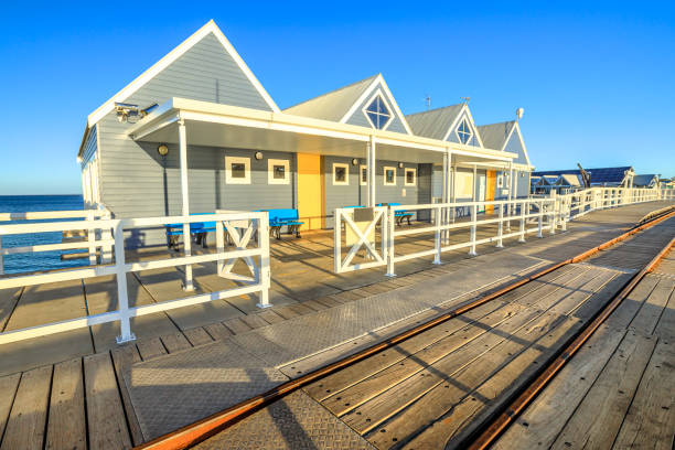 Tracks of railway on Busselton Jetty in Busselton city, Western Australia. The jetty is the longest wooden structure in the southern hemisphere. Famous place. Summer season, blue sky.