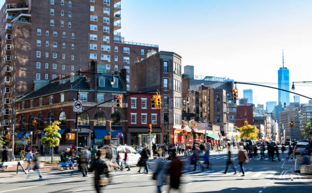 Busy crowds of people walking across the street at 7th Avenue in the Greenwich Village neighborhood of New York City NYC