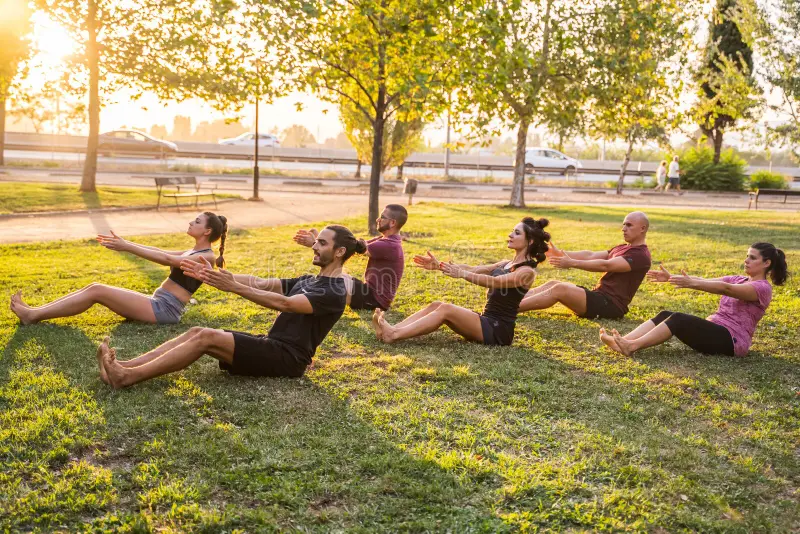 group people practicing yoga outdoors pilates class park 201559919